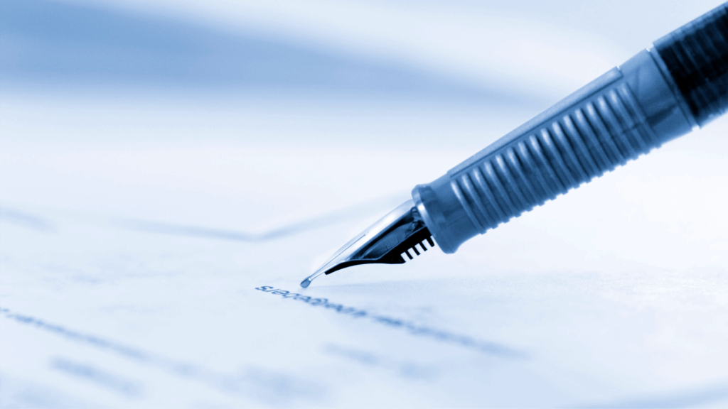 a pen writing on a piece of paper